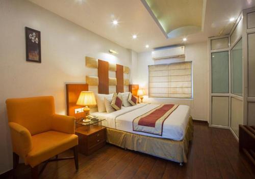 新德里Hotel Palm Do'r Near New Delhi Railway Station的配有一张床和一把椅子的酒店客房