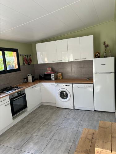 拉西约塔Chalet nature proche plage的厨房配有白色橱柜和洗衣机。