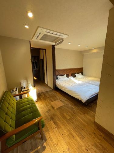 洲本市etoile inn sumoto - Vacation STAY 49252v的一间卧室配有两张床和一张绿色沙发