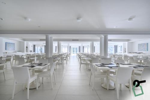 蒂勒尼亚HOTIDAY Hotel Tirrenia的用餐室配有白色的桌子和白色的椅子