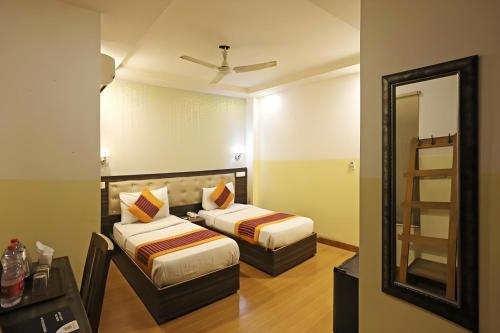 新德里Hotel Aeroporto Near By Delhi International Airport的酒店客房,设有两张床和镜子
