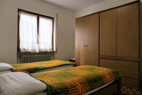 马莱斯科Casa Ezio - Piano terra的一间卧室设有两张床、一个橱柜和一个窗口。