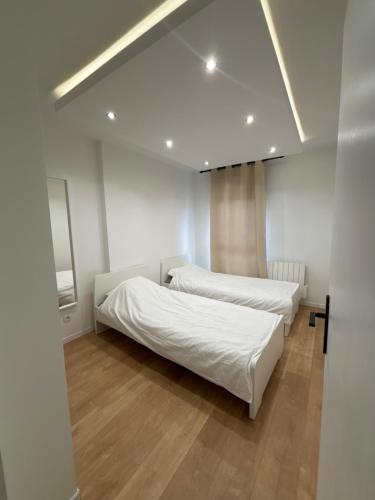 维勒班Appartement moderne的配有白色墙壁和木地板的客房内的两张床