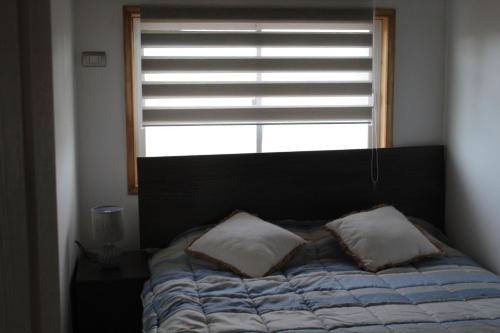 La UniónMaravilloso departamento en el sur de Chile的窗户前的一张带两个枕头的床