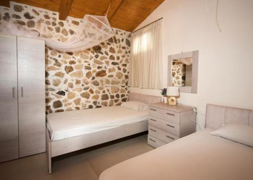 阿齐欧斯·贡多斯Bungalow nefeli的一间卧室设有两张床和石墙