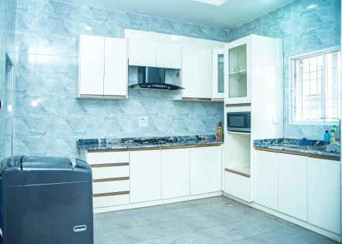 KettiCis service apartment的厨房配有白色橱柜和黑色冰箱。