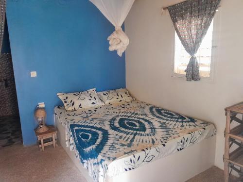 PoponguineCampement Baobab的一间卧室配有一张蓝色墙壁的床