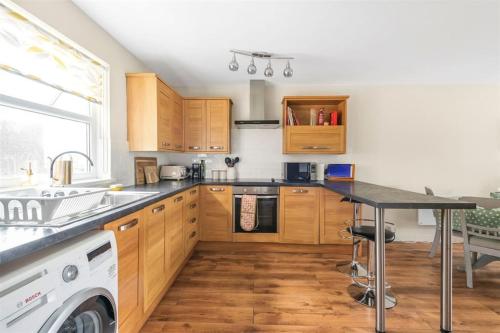 奇切斯特Bright flat in the heart of Chichester的厨房配有木制橱柜和黑色台面