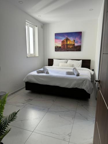 比尔基卡拉Designer 3 Bedroom / Bathroom Apartment in Swatar.的卧室配有一张大床,墙上挂有绘画作品