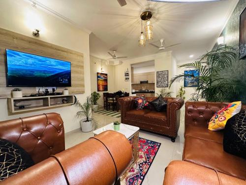 勒克瑙Panaromic Perch With Swimming Pool的客厅配有皮革家具和平面电视