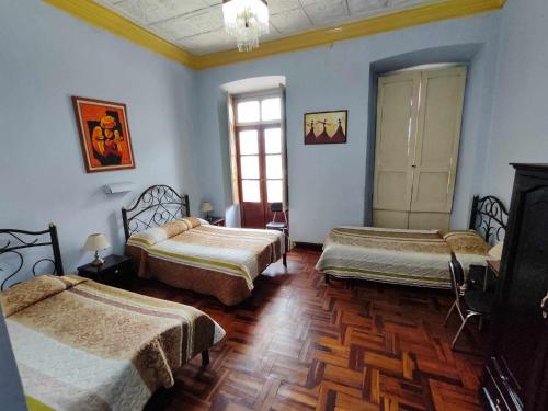 基多胡安娜阿科德旅馆的配有蓝色墙壁和木地板的客房内的三张床