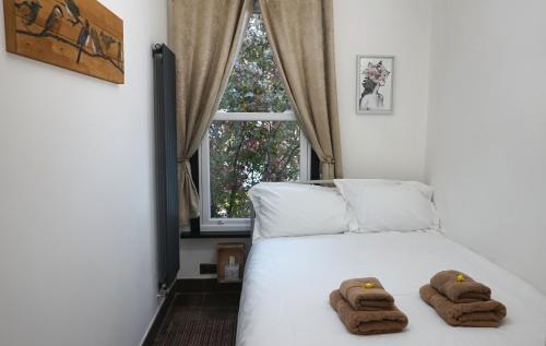 伦敦Beautiful London home sleeps 6, 2 minutes to metro的卧室配有带2条毛巾的窗户,位于床上