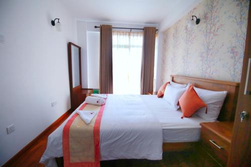 努沃勒埃利耶Nelma's Cosy的一间卧室配有带橙色和白色枕头的床