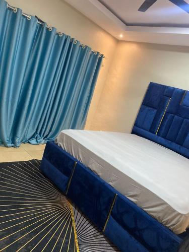 KasoaMagic City Apartments的蓝色窗帘的房间的一张床位