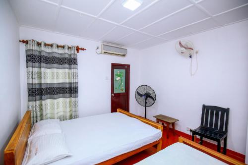 波隆纳鲁沃Villa Ravichini的一间卧室配有一张床、一把椅子和风扇