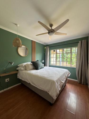 LobambaThe White Rose Home的一间卧室配有一张床和吊扇