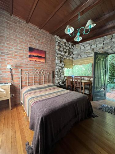 马德普拉塔阿雷胡耶山林小屋的一间卧室设有一张床和石墙