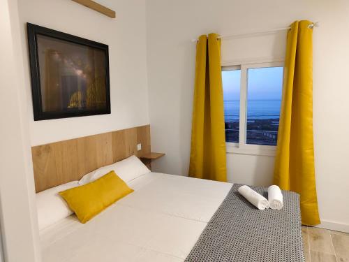 弗龙特拉Hierro的一间卧室配有一张带黄色窗帘的床和一扇窗户