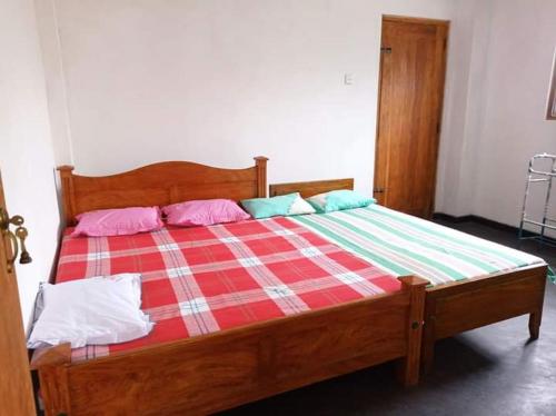 阿努拉德普勒Puraya'S Lodge的一张带粉红色和蓝色枕头的木床