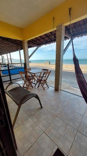 雷东达Chalés Canto do Mar的一个带椅子和吊床的门廊以及海滩
