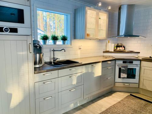 HuutotöyryVuolenkosken Helmi - laadukas ympärivuotinen kohde的厨房配有白色橱柜和水槽