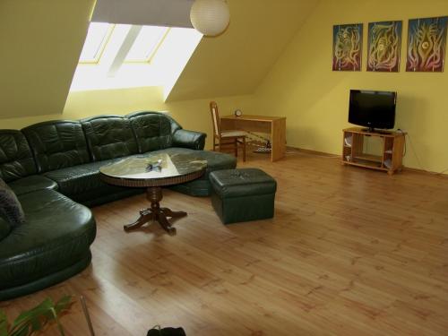 考洛乔Hunyadi Apartment的客厅配有黑色真皮沙发和桌子