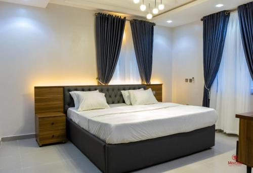 阿布贾99 MOZILLA APARTMENTS AND SUITES的一间卧室配有一张带蓝色窗帘的大床