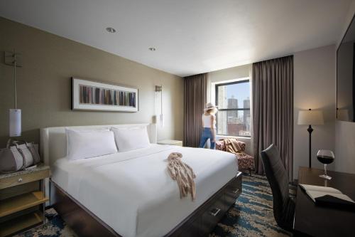 芝加哥菲利克斯酒店的一间酒店客房,配有一张床和一个女士,从窗户望出去