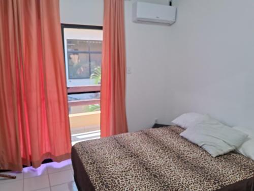 萨尔瓦多VILLAGE PÉ NA AREIA的一间卧室配有床和红色窗帘的窗户