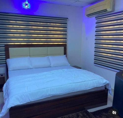 拉各斯Optimum Residence的一间卧室配有一张带白色床单的大床