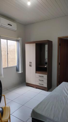 巴纳伊巴Casa Caminho da Alvorada的一间卧室配有一张床和一个带电视的橱柜