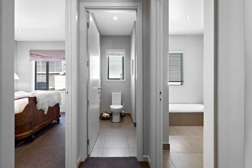 箭镇Elite Holiday Homes Queenstown - Arrowbrae的一间卧室配有一张床,浴室设有卫生间
