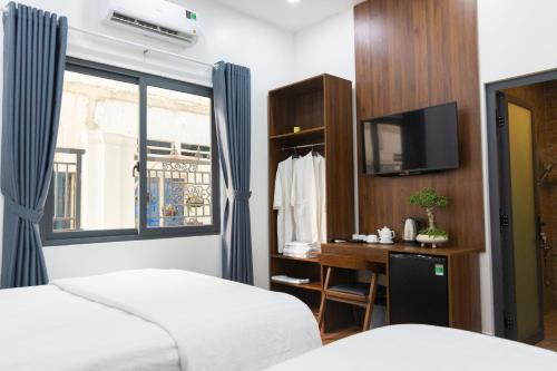 Trảng BàngGems Hotel - Khách sạn Trảng Bàng的一间卧室设有两张床、一台电视和一扇窗户。
