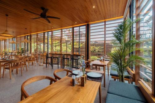 坎古Canggu Cabana Resort By Ini Vie Hospitality的餐厅设有桌椅和大窗户。