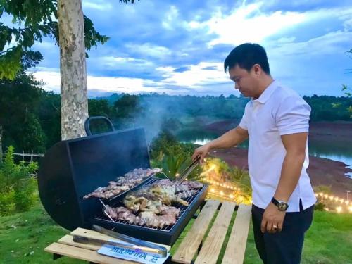 Gia NghĩaDak Nguyen Homestay & Farm 3的男人在烤架上烹饪肉