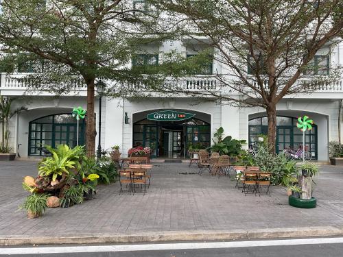 富国Green Inn Phu Quoc Hotel的大楼前的咖啡馆,带桌椅