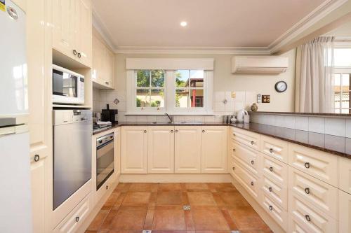 奥尔伯里Porters Cottage Oasis的一间大厨房,配有白色的橱柜和水槽