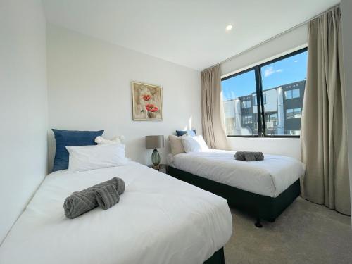 奥克兰Your Modern Home in Sandringham, Close to City, Heat Pumps, Netflix, Parking的酒店客房设有两张床和窗户。