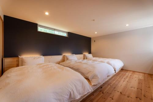 安昙野市北アルプス山麓の貸切サウナと貸別荘Azumino36stay的卧室设有两张床,墙上设有窗户。