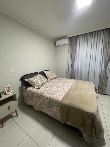 GuaramirimCasa com quarto disponível em Guaramirim的一间卧室配有一张床,床头柜配有桌子