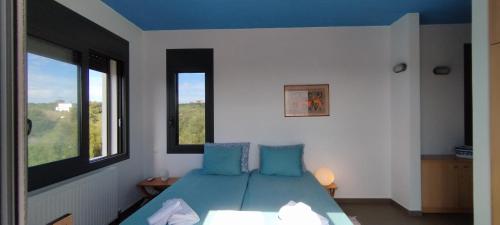 KamáriaLIOFYTO - Stylish villa with views to Foinikounda bay的一间卧室配有一张带蓝色枕头的床和一扇窗户。