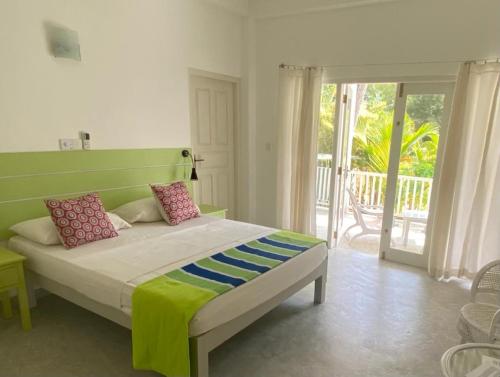 希克杜沃Plantation House的一间卧室配有一张带绿色床头板的床