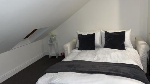 伦敦Sunrise Retreat的客房内的一张带黑色枕头的白色床