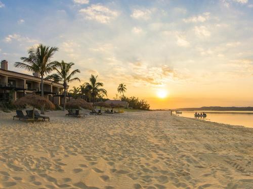 普拉伊拉多比莱尼圣玛迪合海滩俱乐部度假村的日落时分,海滩上摆放着椅子和棕榈树
