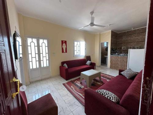 赫尔格达Skylen Hostel的客厅配有红色的沙发和桌子