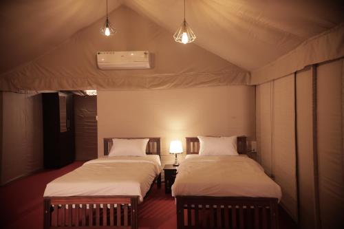 LakkidiAnamala Serenity Homestay Kerala的帐篷间内的两张床和两盏灯