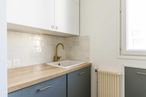 勒瓦卢瓦-佩雷Charming Appt Levallois Perret的厨房配有水槽、白色橱柜和散热器