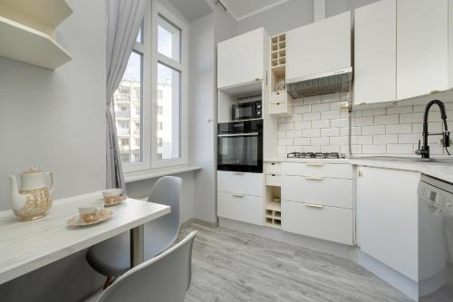 弗罗茨瓦夫Spacious 3-Bedroom Apartment Plac Grunwaldzki Wrocław by Renters的厨房配有白色橱柜和桌椅
