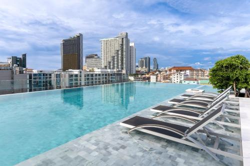 芭堤雅市中心Amethyst Hotel Pattaya的一座带躺椅的建筑屋顶上的游泳池