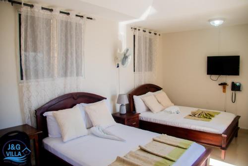 海地角J&G Villa Hotel的一间卧室设有两张床,墙上配有电视。